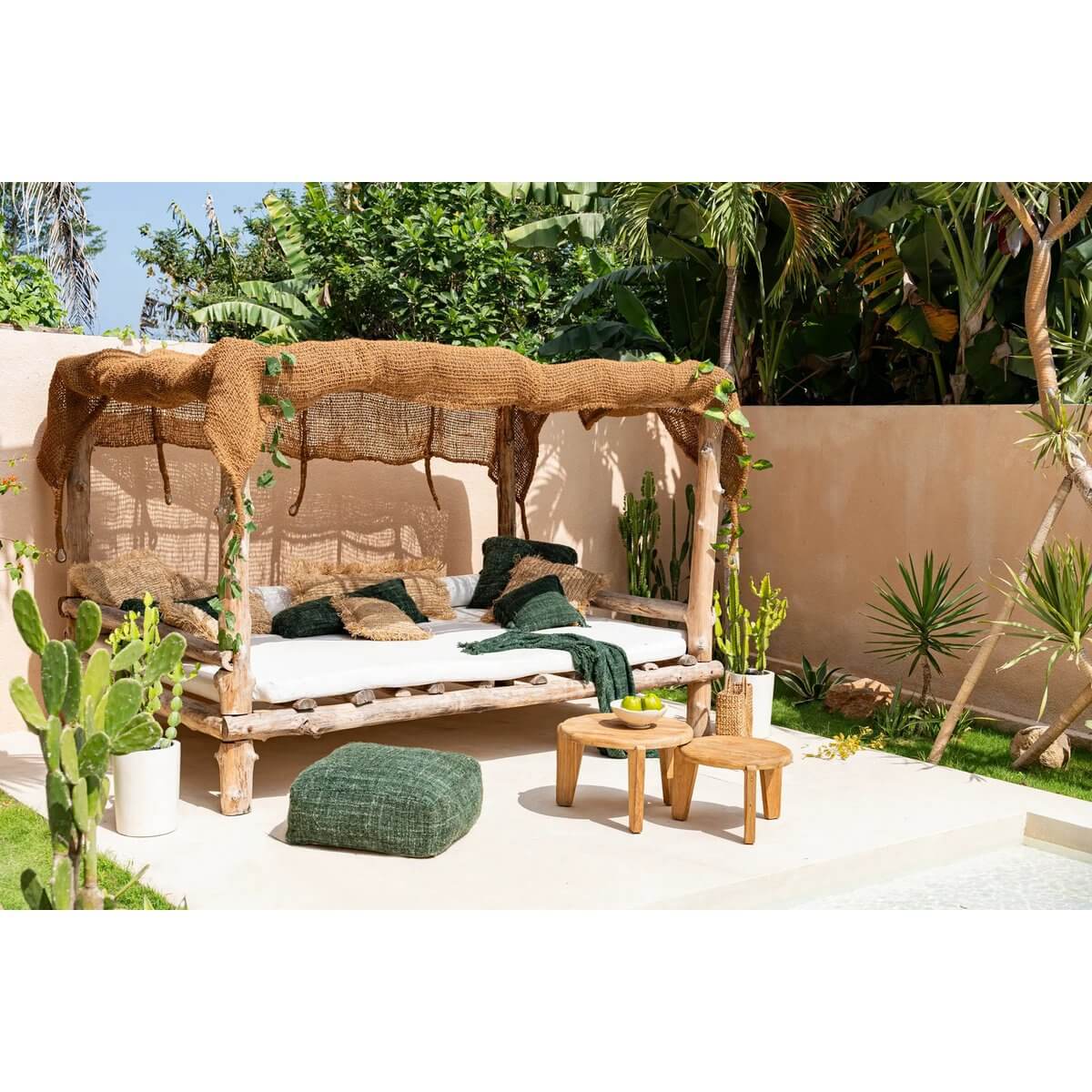 Bohemian outdoor setup with natural coco shade canopy over a cozy lounge area, surrounded by lush greenery and wooden furniture.