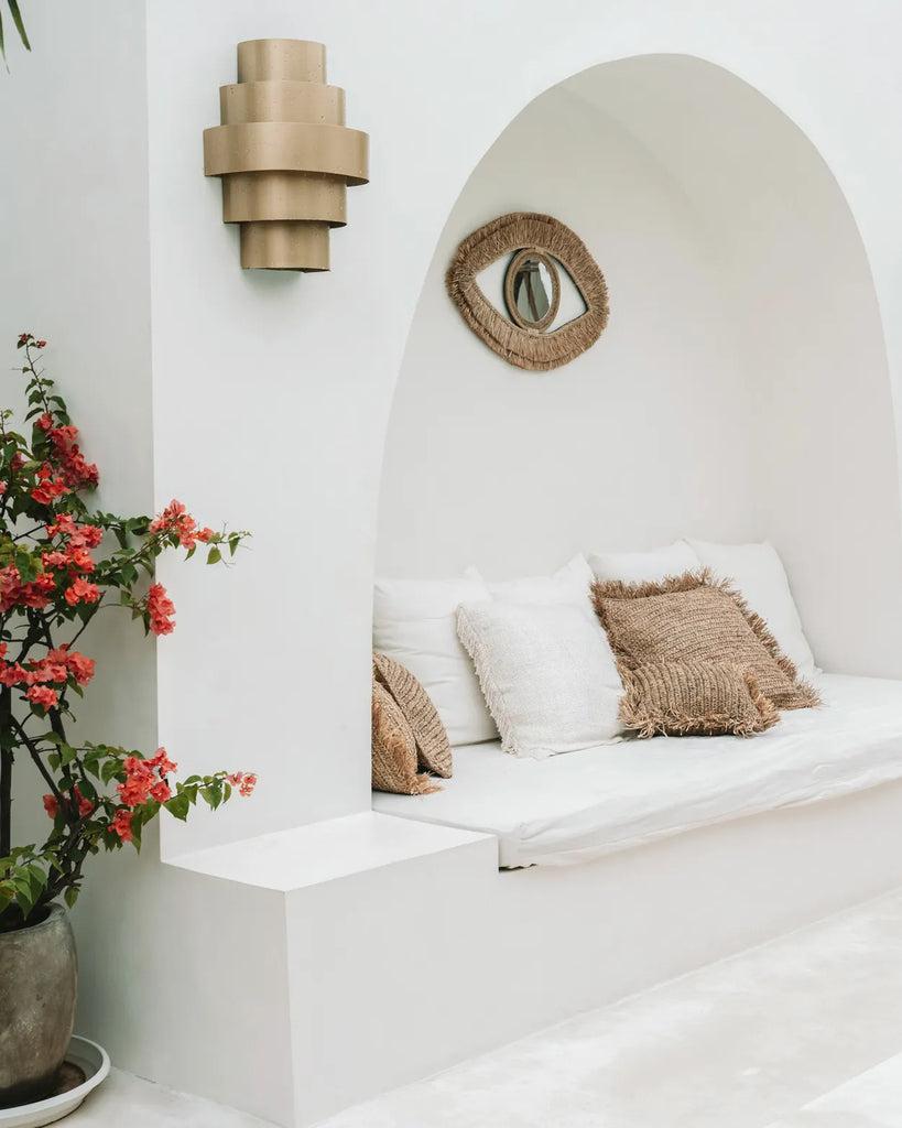 Gezellig boho zithoekje met Raffia Eye Mirror en zachte kussens, perfect voor een rustiek interieur.