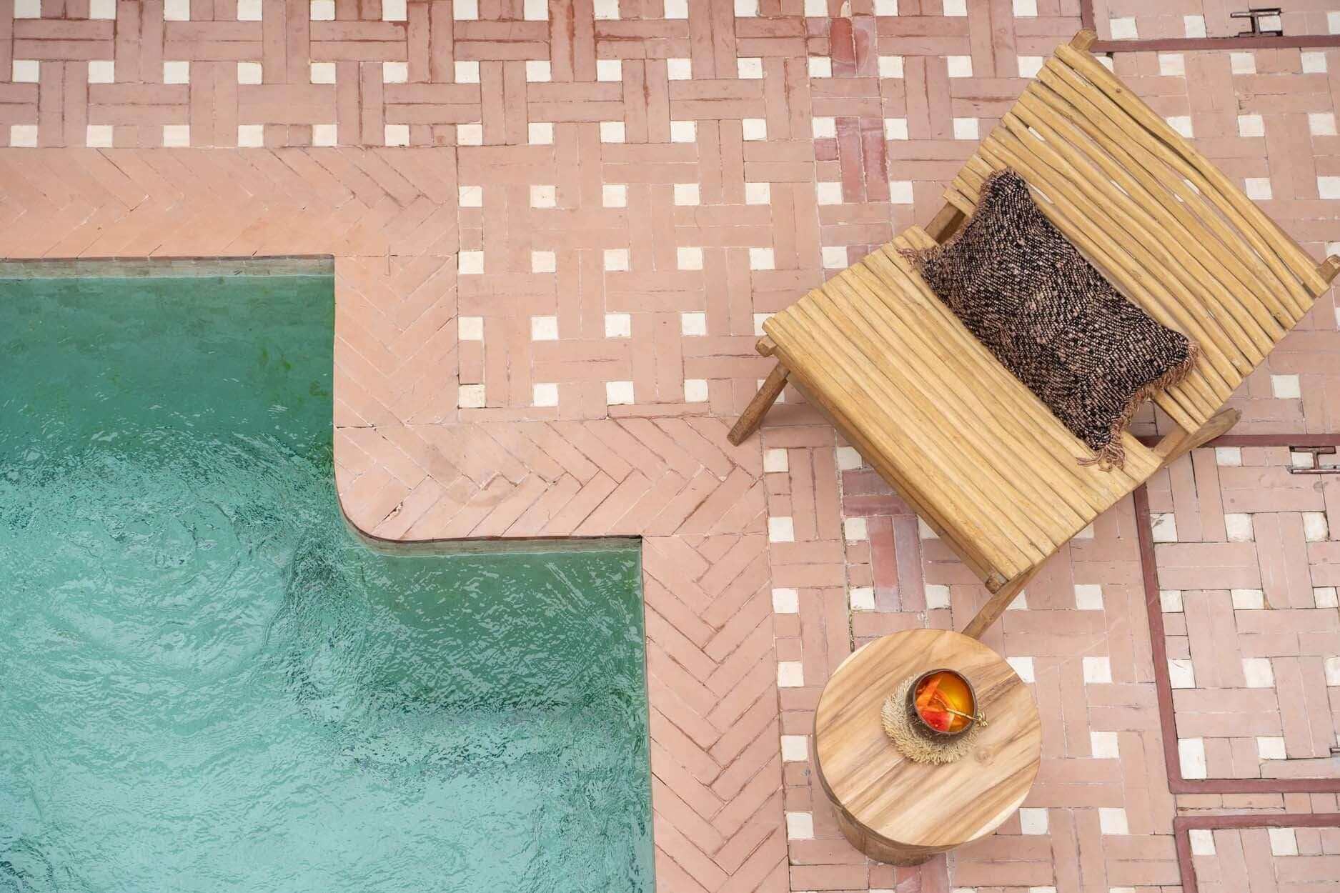 Boho stoel de Islander naast zwembad, gemaakt met teakhouten spijlen, perfect voor ontspannende zomeravonden buiten.