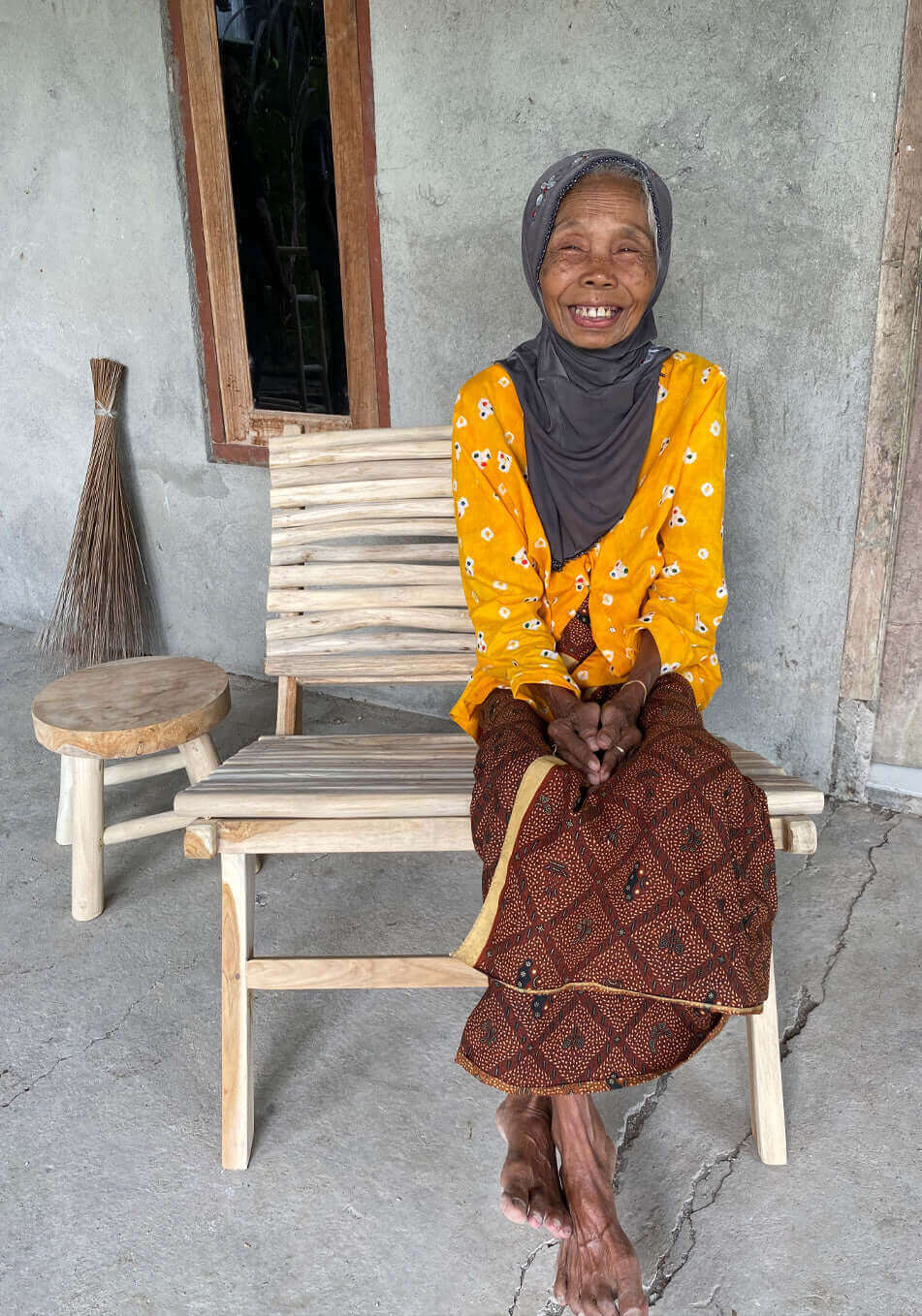 Vrouw op Boho stoel de Islander, handgemaakt van teakhout, geniet van een zonnige dag.