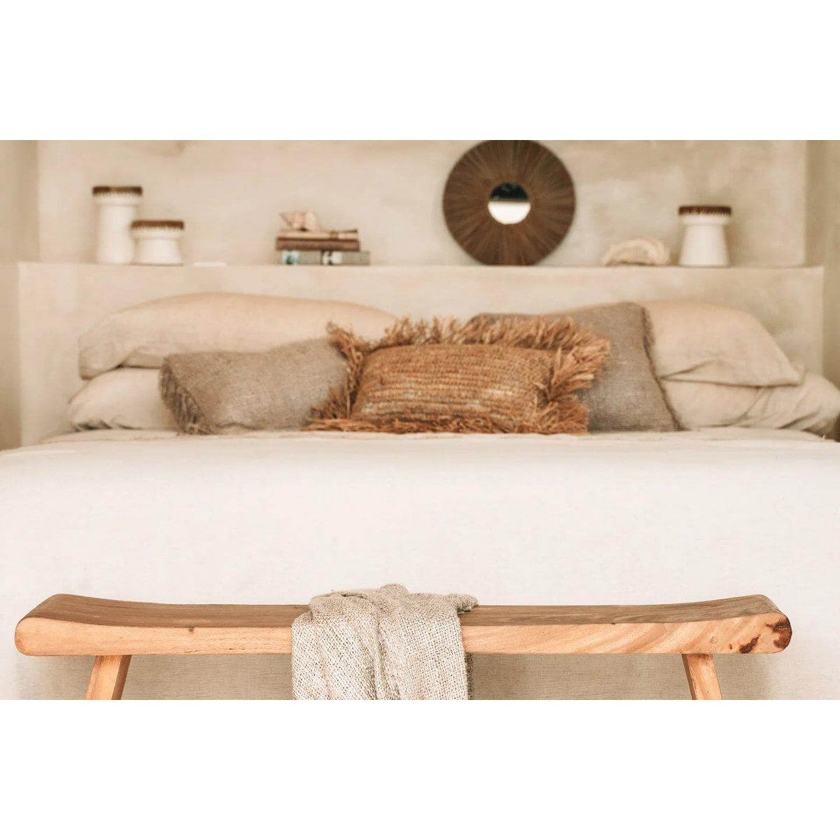 Chique slaapkamer met kuststijl, spiegel van zeegras, houten bank en beige tinten voor een warme, boho sfeer.