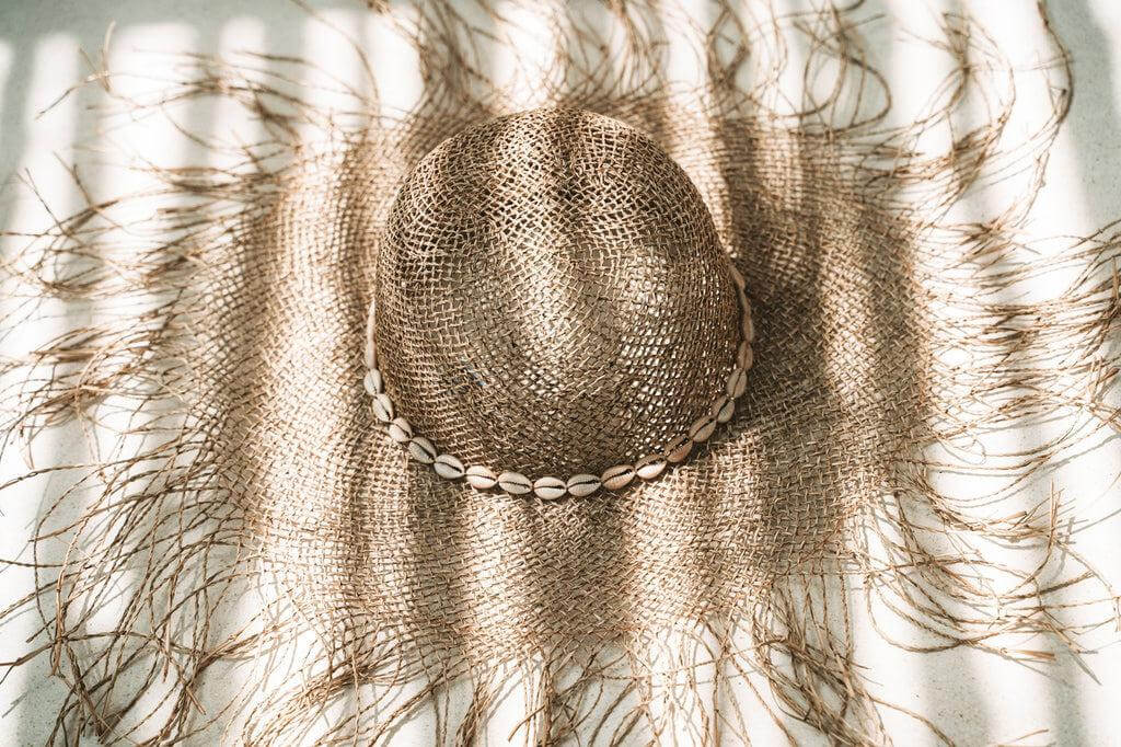 Zomerse strandhoed van zeegras met schelpendecoratie in de zon, ideaal voor stijl en bescherming op zonnige dagen.