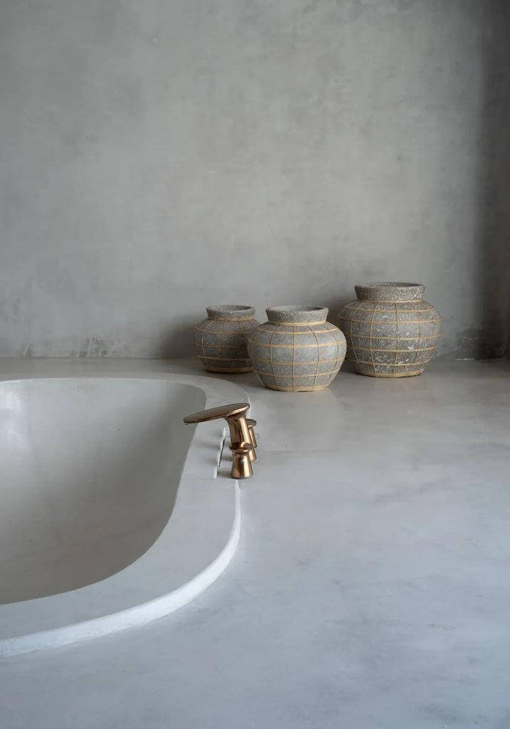 Stijlvolle terracotta vazen met rotan details naast een moderne badkuip, perfect voor droogbloemen, met een Beton Naturel uitstraling.