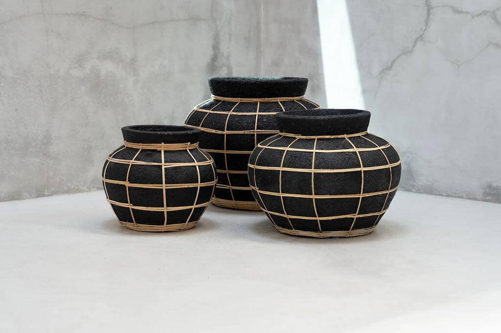 Drie De Belly terracotta vazen met rotan detail in zwart en naturel, ideale droogbloemvazen voor kustvibes in huis of tuin.