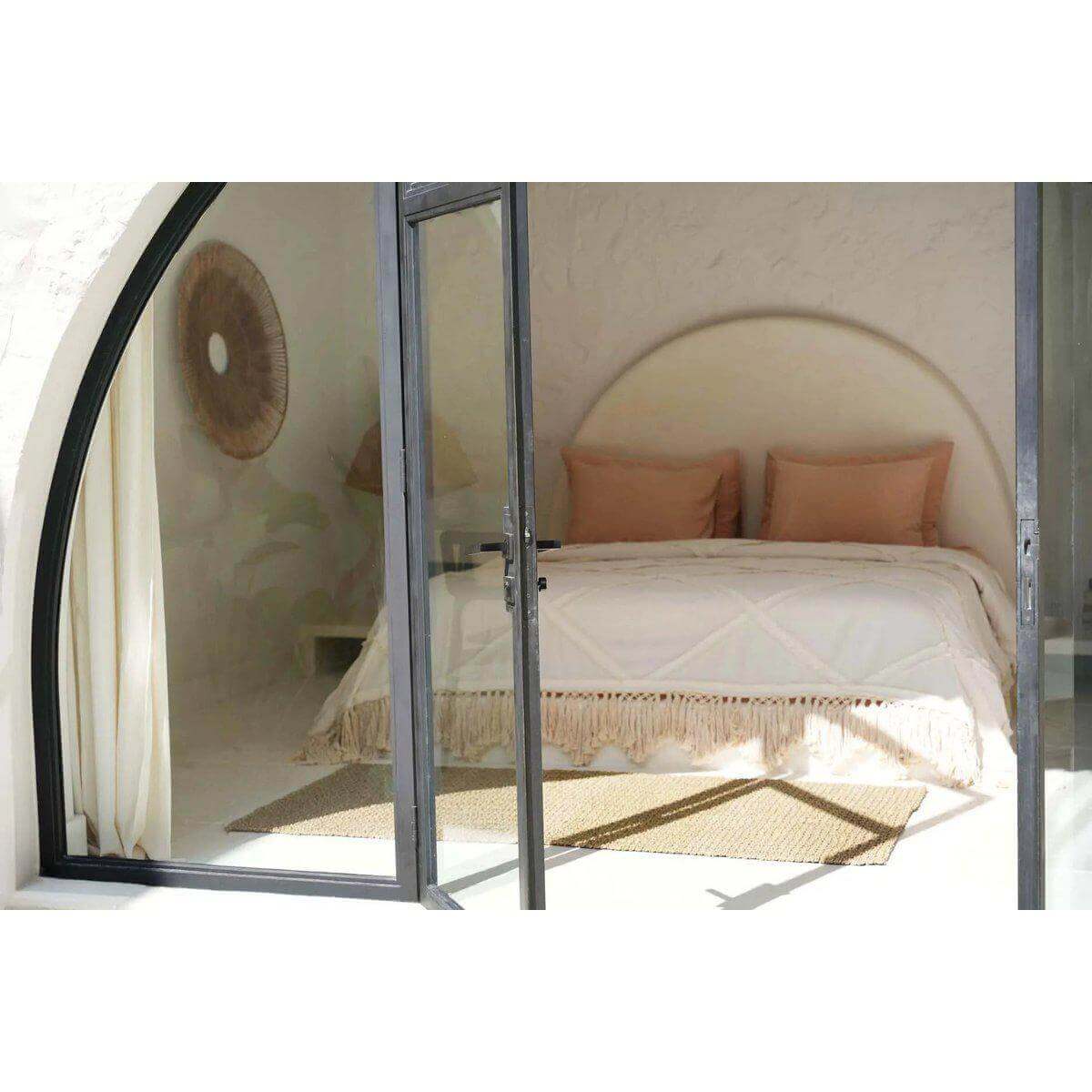 Sfeervolle slaapkamer met natuurlijke Berber bedsprei in neutrale tinten, stralend in het zonlicht.