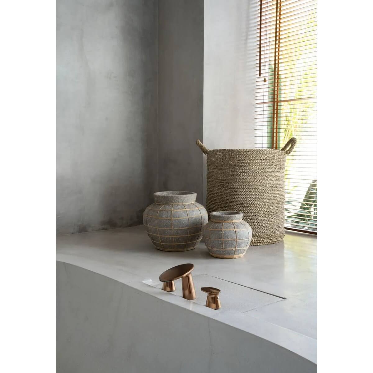Alt Tag: Terracotta buikvazen met rotandetail en mand op moderne tafel, ideaal voor droogbloemen, creëert een kustsfeer in elke ruimte.