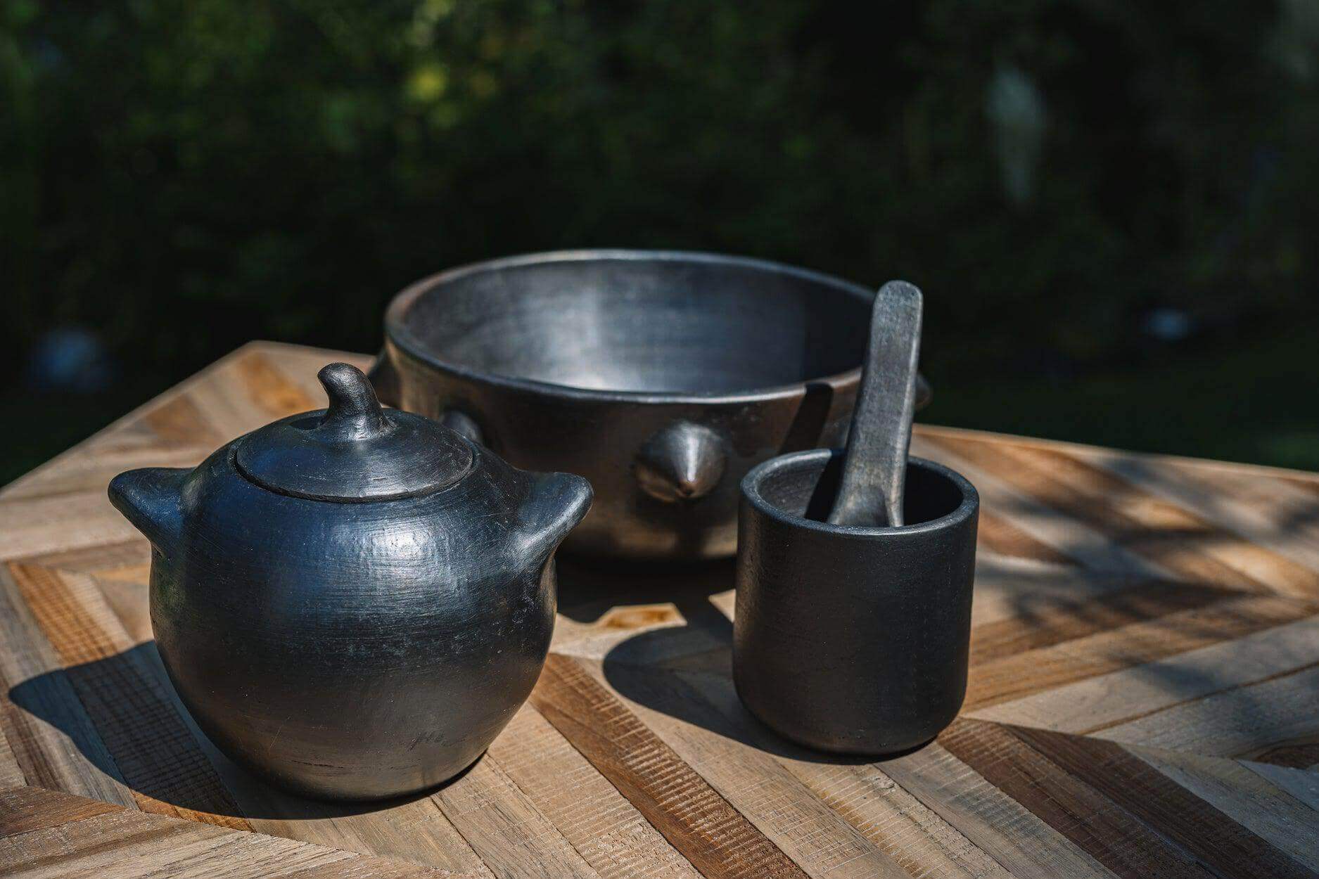 Zwart-gebrande serviescollectie inclusief beker, kom en theepot op houten tafel. Perfect voor kleurrijke, Insta-licious maaltijden.