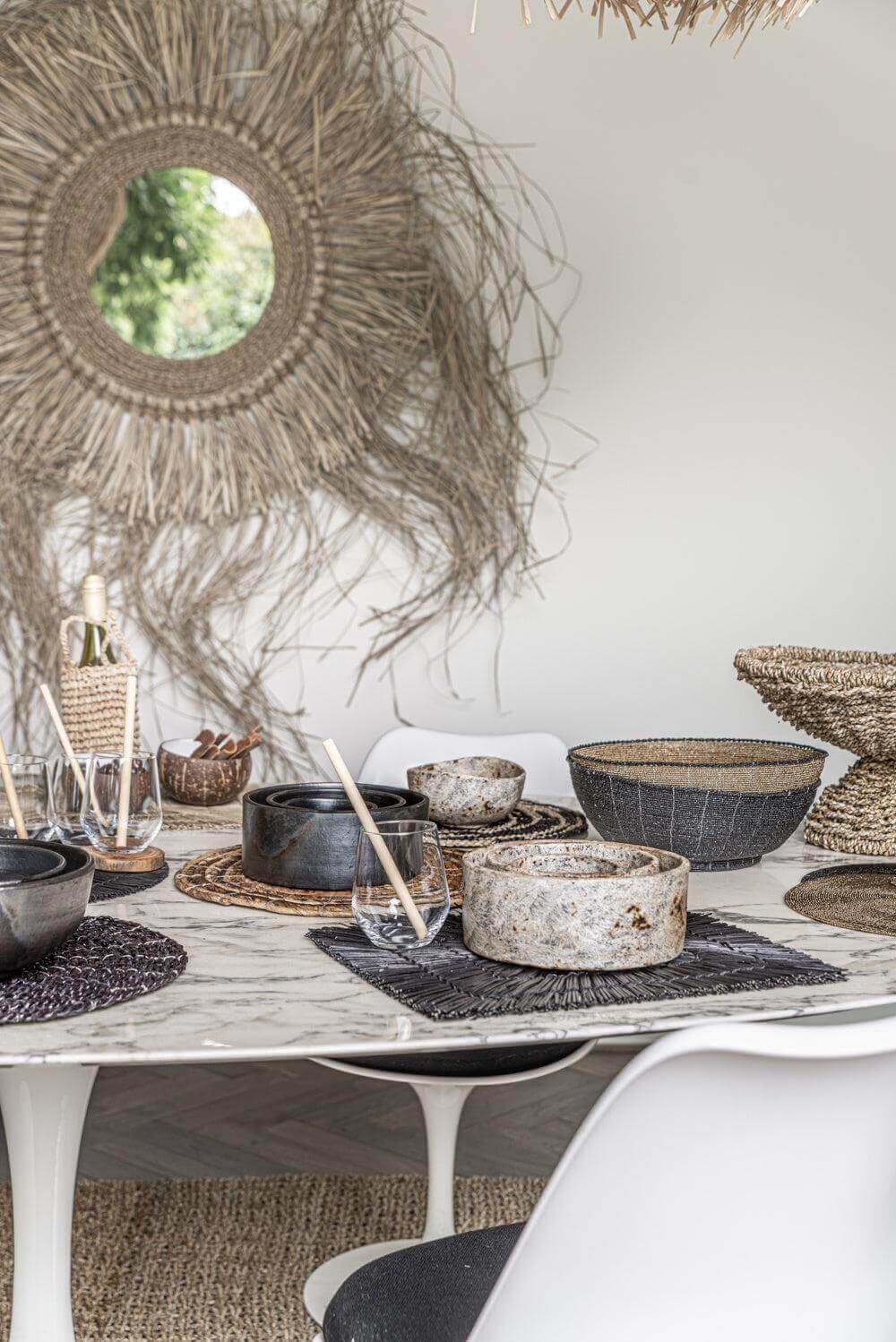 Moderne eetkamer met stijlvolle kommen set van drie op een marmeren tafel, omringd door rustieke decoraties en spiegeldetail.