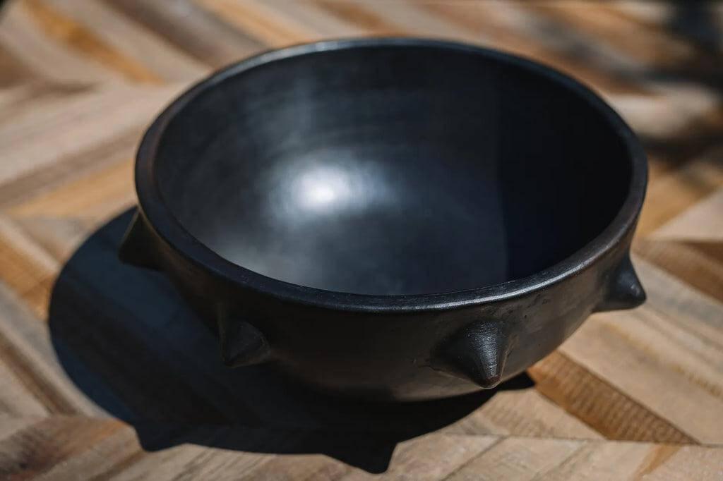 Zwarte teakhouten kom met strak design, ideaal voor het opbergen van accessoires of het presenteren van hapjes. Handgemaakt, maten variëren.