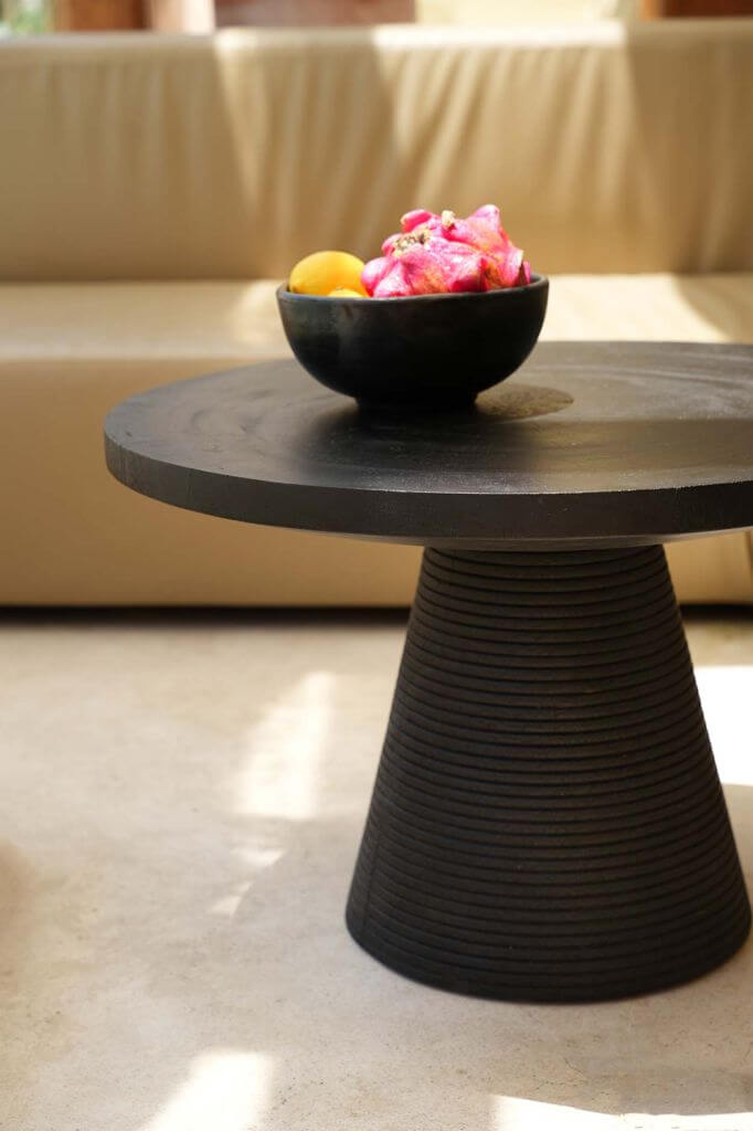 Zwarte terracotta kom op moderne tafel met bloemen en citrusvruchten, perfect als uniek serviesstuk; vaatwasmachinebestendig. Hoogte 9cm, breedte 20cm.