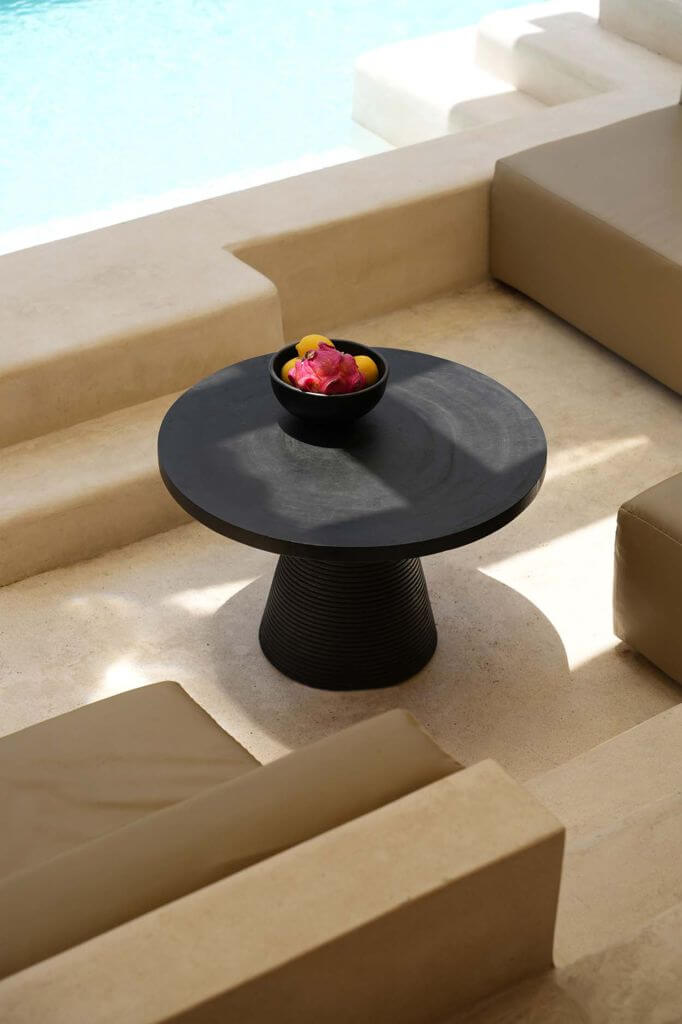 Stijlvolle ruimte met moderne zwarte tafel en kleurrijke fruitschaal naast een zwembad, perfect voor luxe ontspanning.