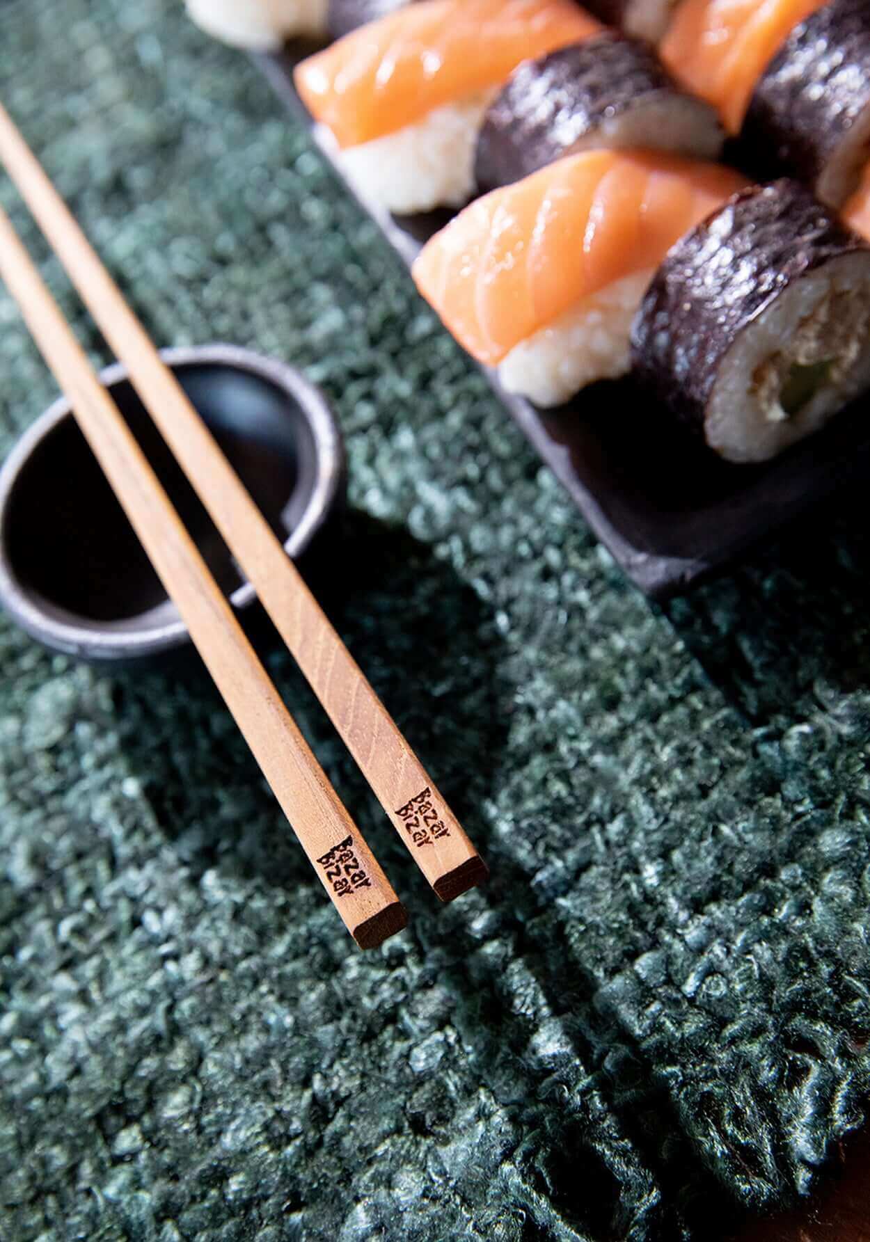 Sushi op groen tafelkleed met houten stokjes en sojasauskommetje, een perfecte Japanse maaltijdopstelling.