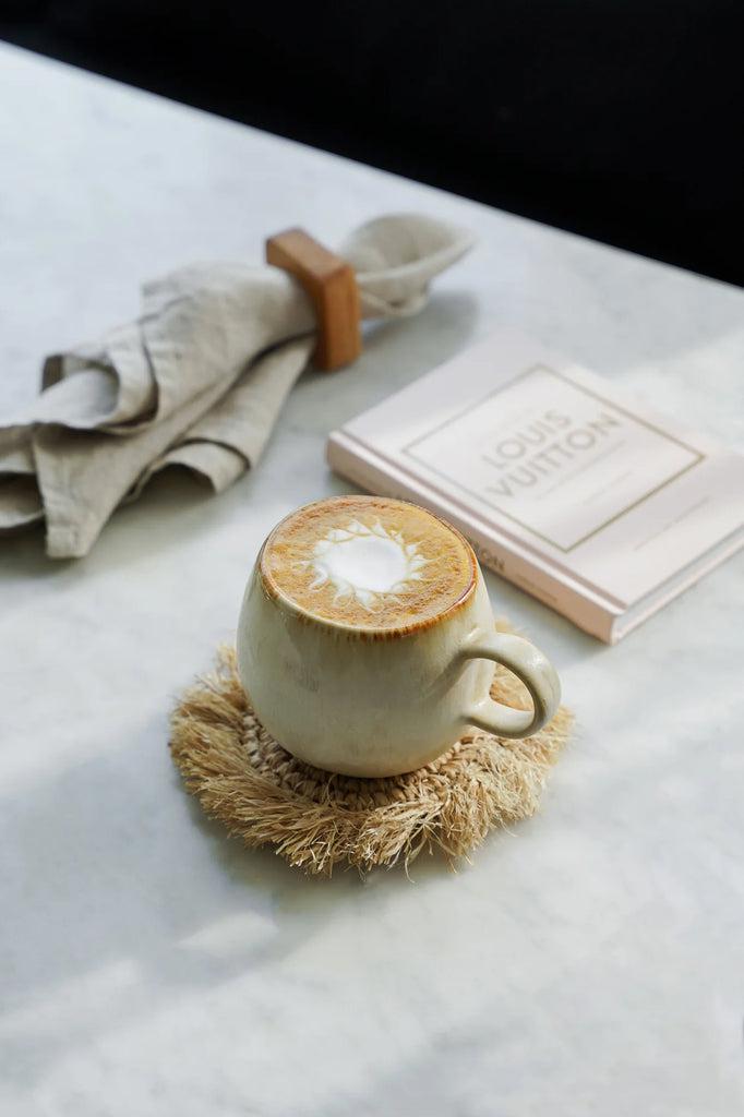Eettafel met een De Cascais koffiemok en een boek, perfect voor een stijlvolle brunch of koffiepauze.
