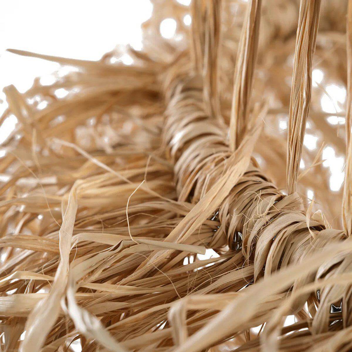 Close-up van de handgemaakte Casita hanglamp van natuurlijk mendonggras met decoratieve franjes voor lichteffecten.