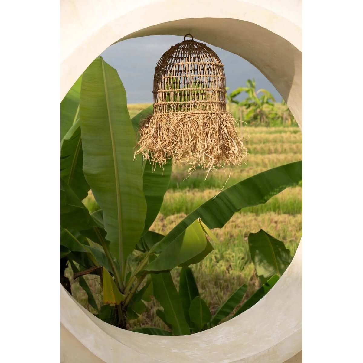De Casita hanglamp in een tropische setting, handgemaakt van mendonggras met natuurlijke franjes, ideaal voor een exotische sfeer.