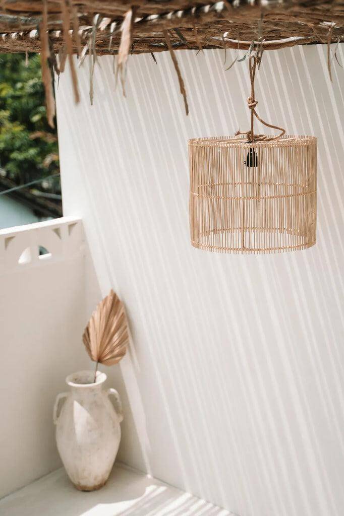Natuurlijke rotan hanglamp op lichte achtergrond, creëert elegante schaduwen. Ideaal voor binnen of overdekte buitenruimtes.