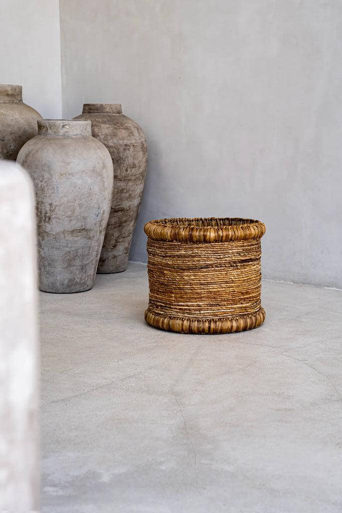 De Chuka mand handgeweven van waterhyacint en bananenblad, elegante opbergoplossing, decoratieve ronde mand in moderne ruimte.