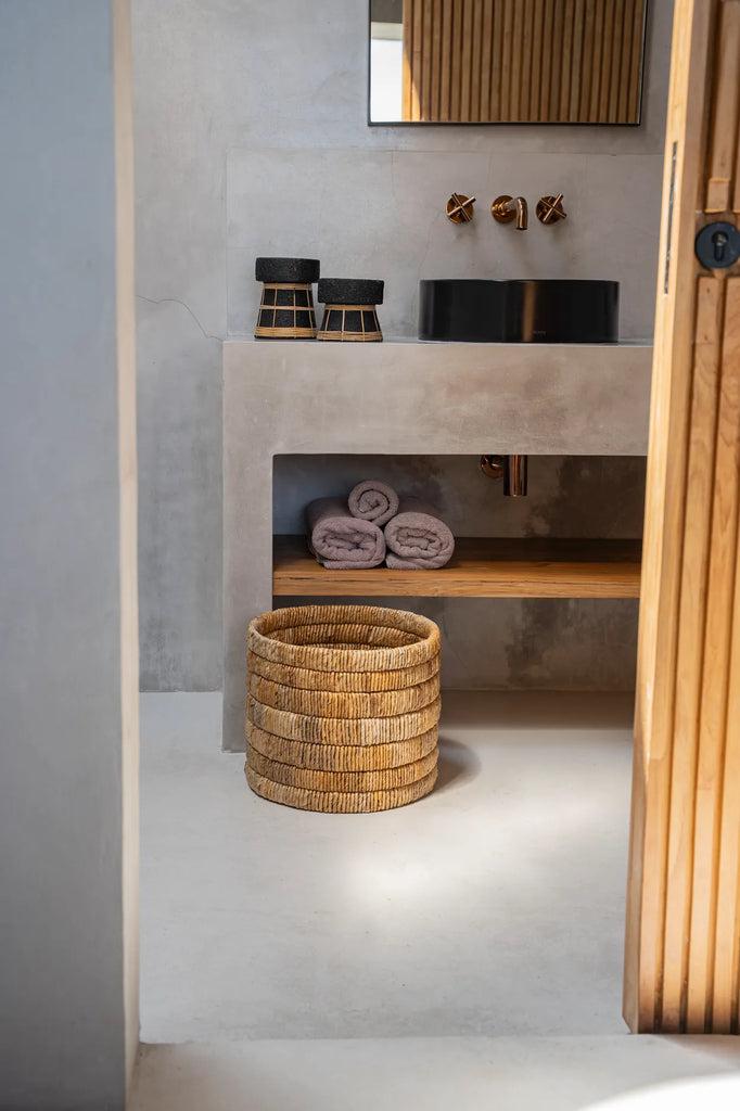 Handgeweven De Chuma Mand van bananenblad in een moderne badkamer met houten details, een stijlvolle opbergoplossing.