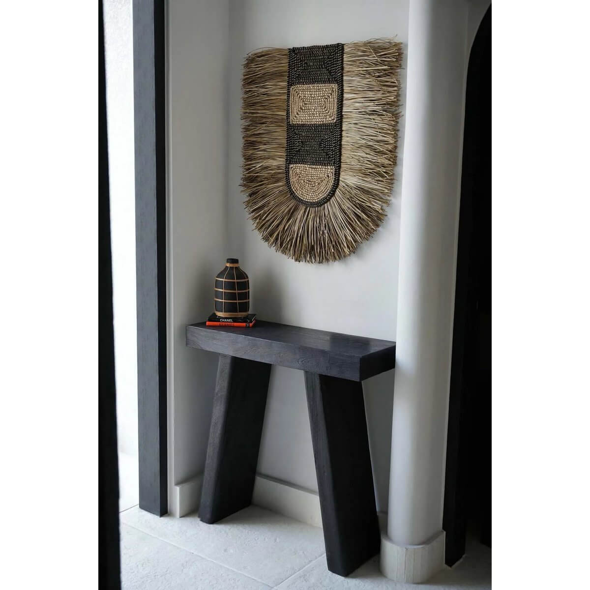 Bohemian-style wall decor with natural grass fibers on a minimalist black table, enhancing modern interiors with artistic flair.