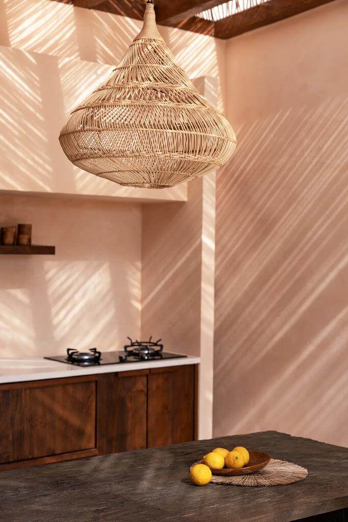 Alt Tag: Rotan De Drop Hanglamp in natuurlijke kleur, sfeervol verlichtend een moderne keuken met houten details en rieten patronen.