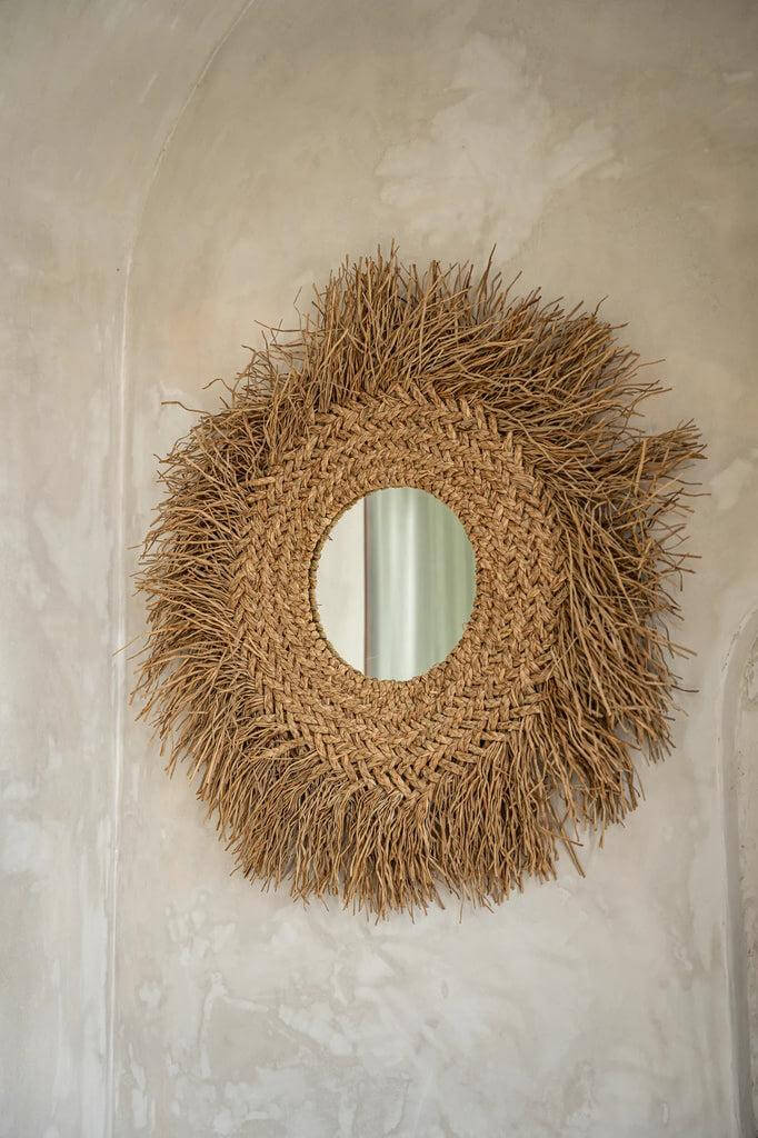 De Early Monday rotan spiegel met franjes, boho design, natuurlijke kleuren. Perfecte kusttextuur voor elk interieur. Diameter glas: 25 cm.