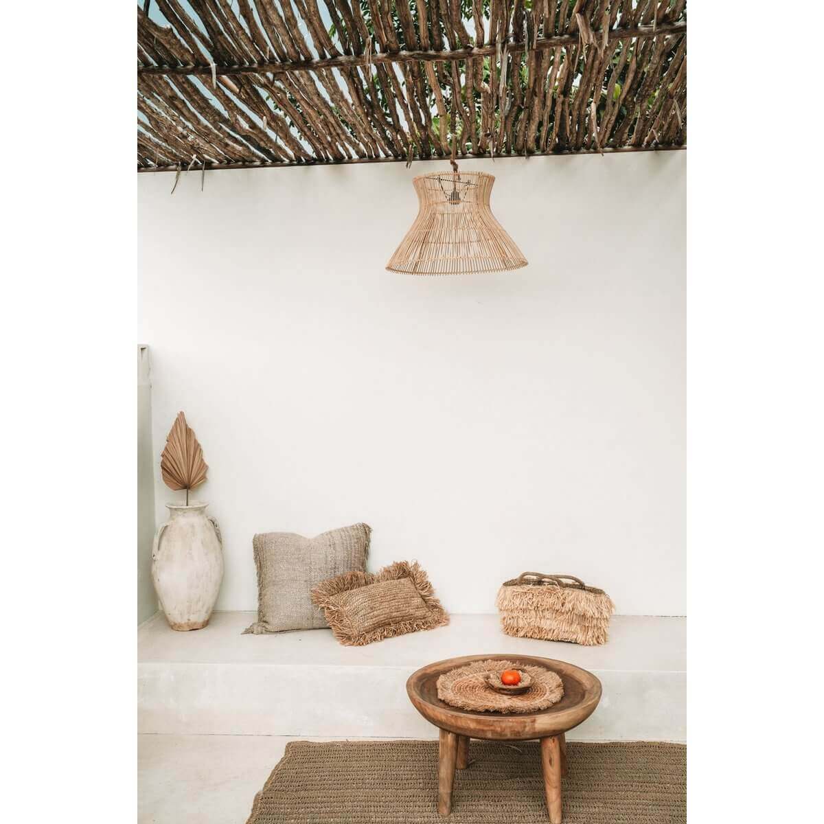 Rotan hanglamp in stijlvolle kamer met houten tafel en natuurlijke decoratie, ideaal voor binnen of overdekte buitenruimtes.