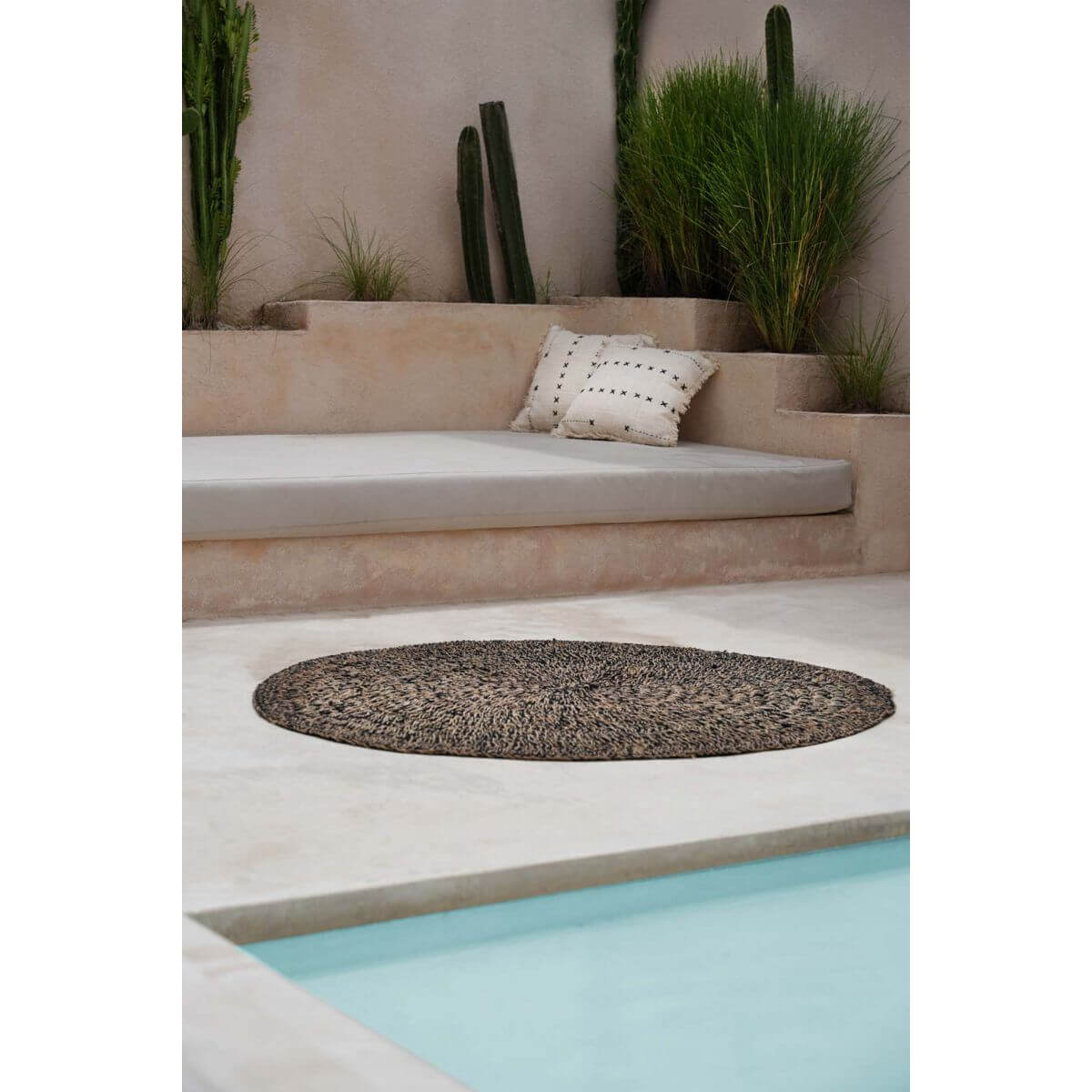 Oase van rust met loungehoek, tropische planten en rond vloerkleed bij zwembad