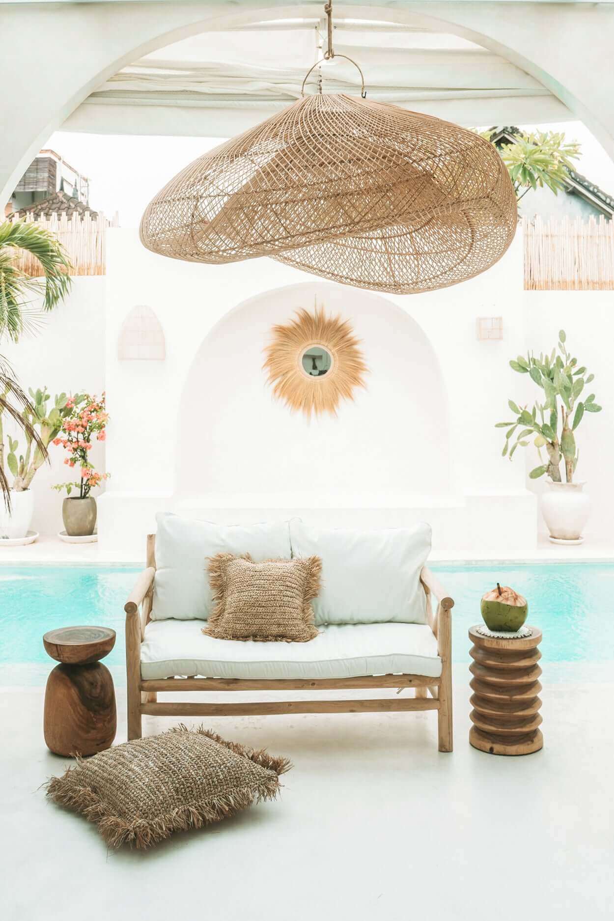 Luxe buitenruimte met rotan decor, houten krukje en zwembad. Perfect voor zomerse ontspanning in een stijlvolle setting.