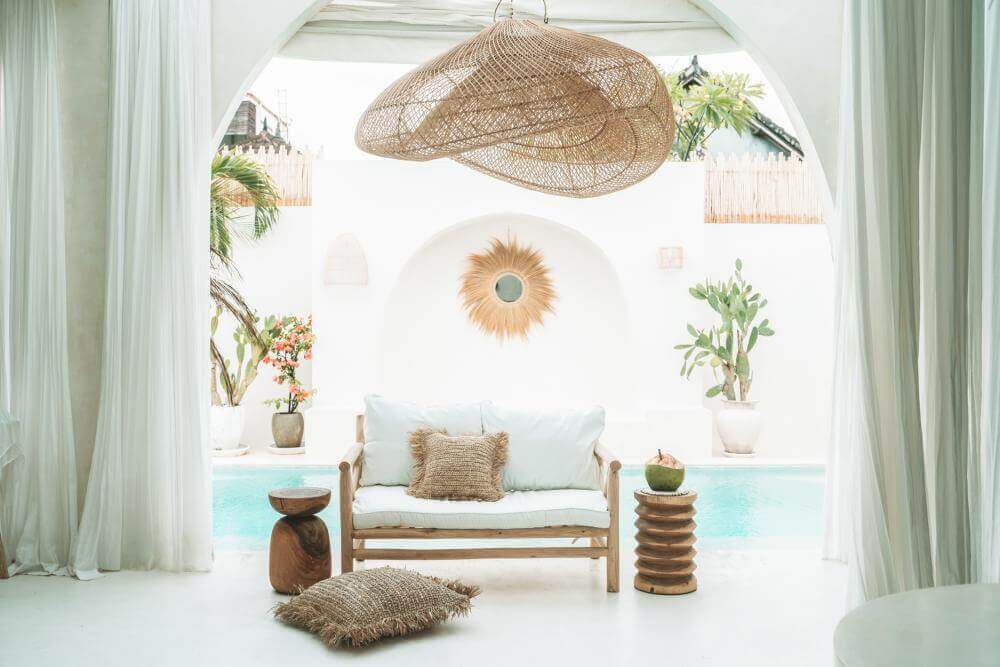 Luxe wit interieur met houten meubels en planten bij zwembad, zomerse sfeer.
