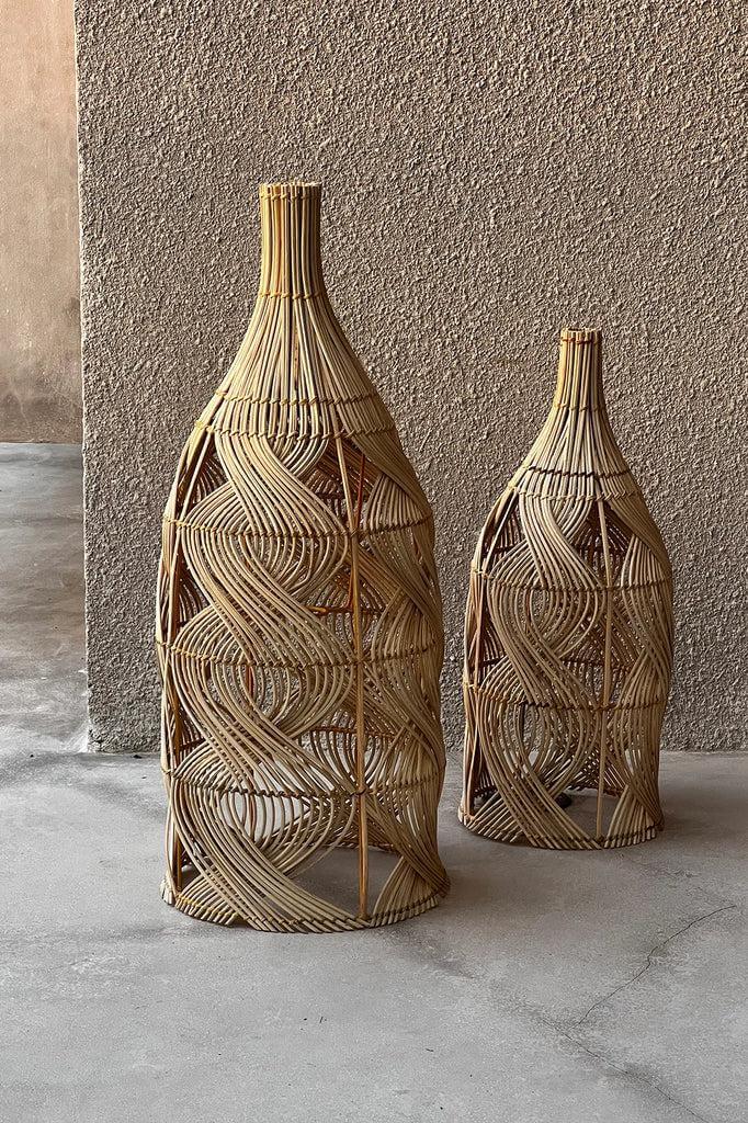 Twee natuurlijke rotan hanglampen De Garaffa in flesvorm, veelzijdig als vloerlamp of tafellamp, perfect voor een nachtkastje.