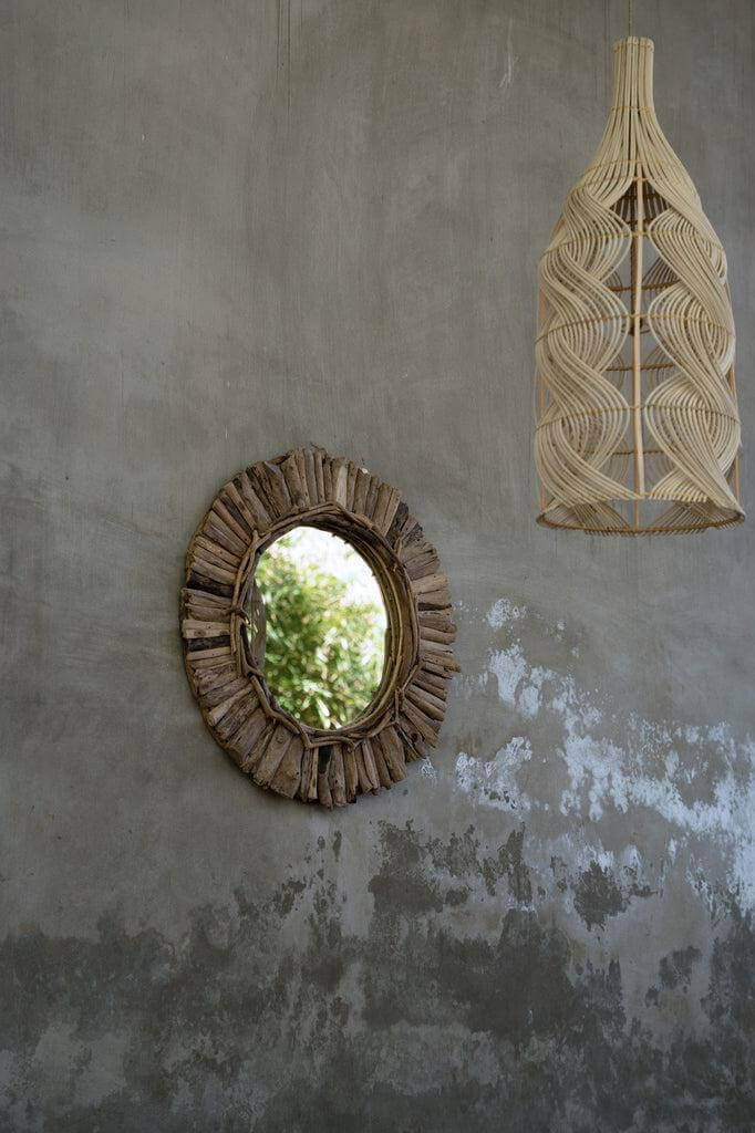 Natuurlijke rotan hanglamp en spiegel voor een rustieke wanddecoratie.