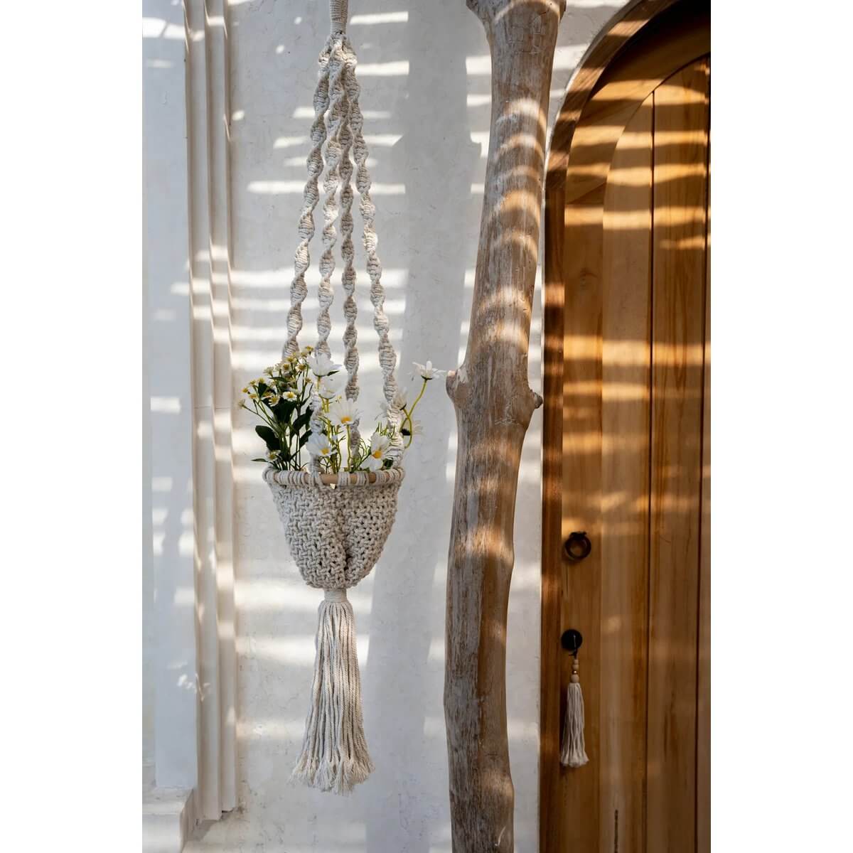 Macramé plantenhouder naturel wit hangt met bloemen, handgemaakt katoen, 135cm lang, in een sfeervol interieur.
