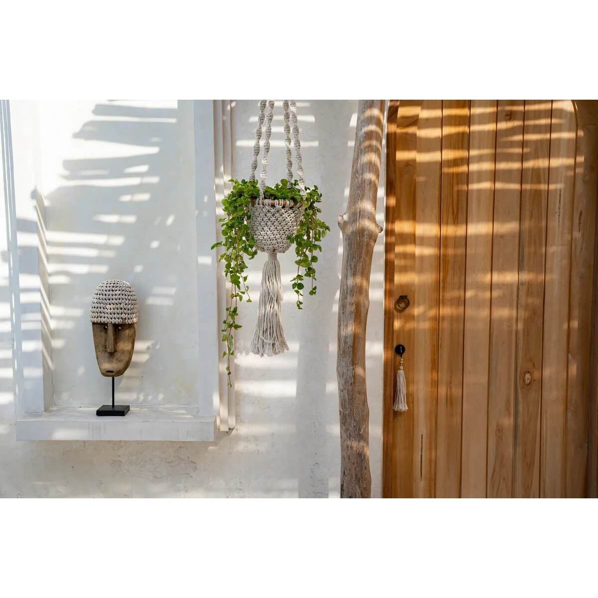 Handgemaakte gedraaide macramé plantenhouder in natuurlijk wit met groene plant, decoratief binnen of overdekt buiten.