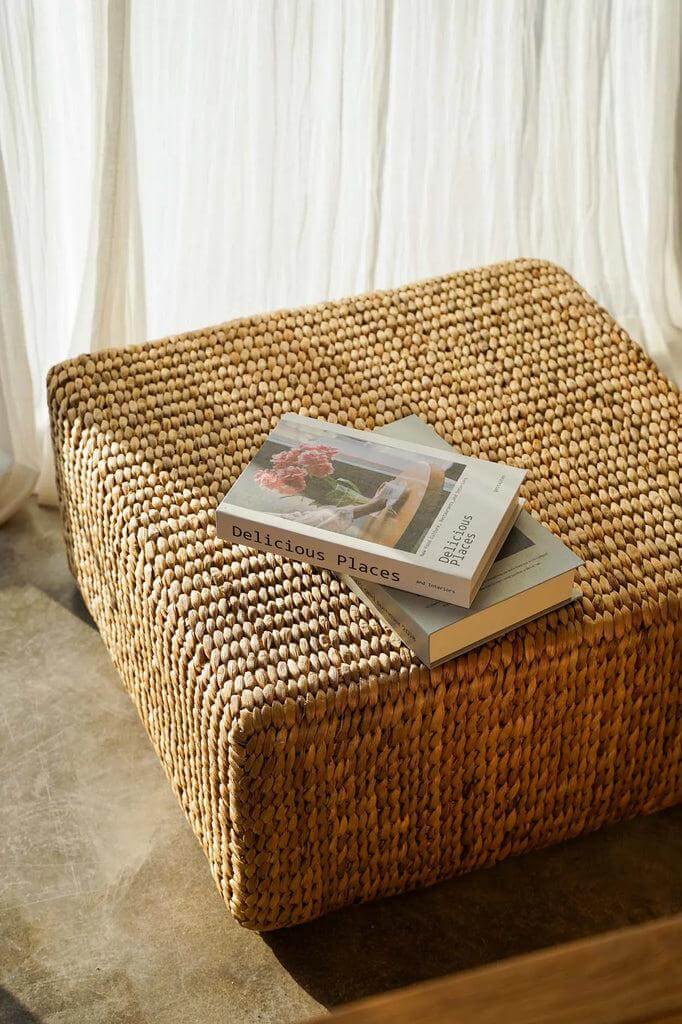 Vierkante poef van waterhyacint met boeken erop voor een natuurlijke touch in interieur.