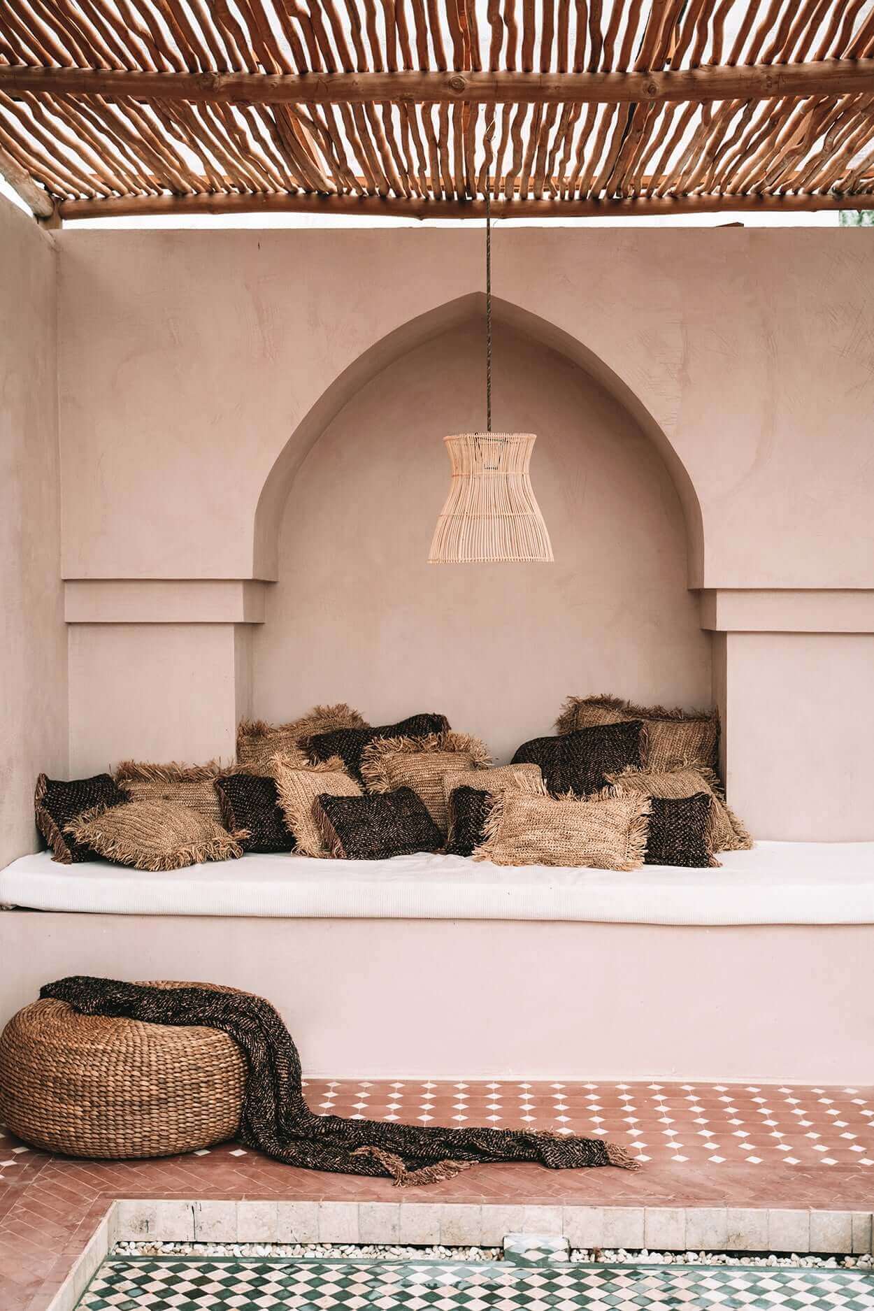 Boho lounge ruimte met decoratieve kussens en Hyacinth Poef, ideaal voor tuin of terras, duurzame natuurlijke materialen.