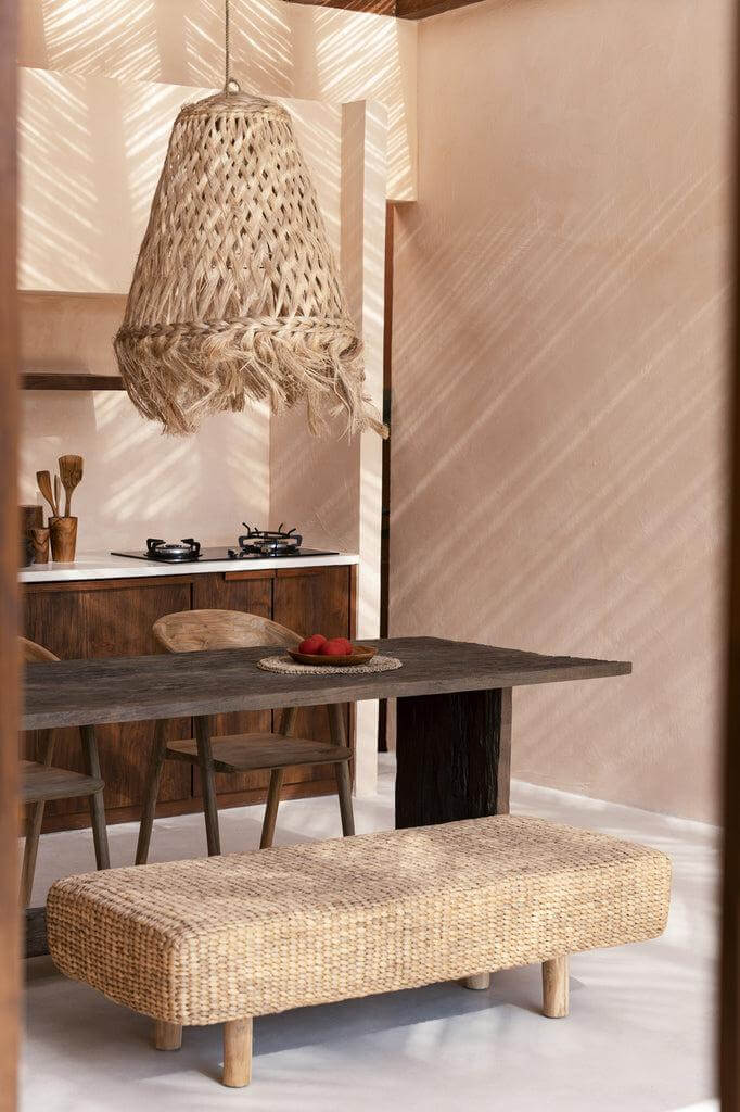 Handgemaakte Abaca Jelly Fish hanglamp in natuurlijke kleur boven houten tafel met rieten bankje in interieur.