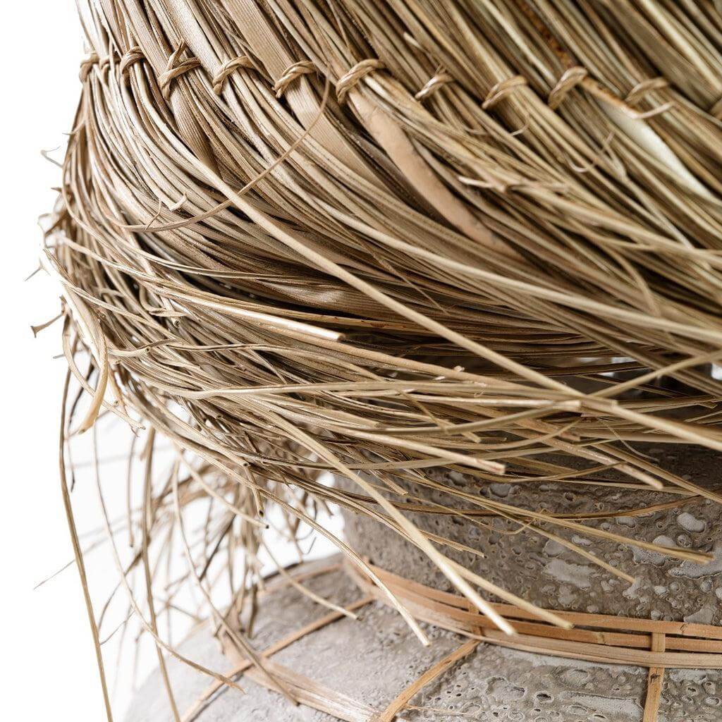 Close-up van de Lipsi tafellamp met een betongrijze terracottavoet en rotan pandangras lampenkap. Sfeervol en natuurlijk ontwerp.