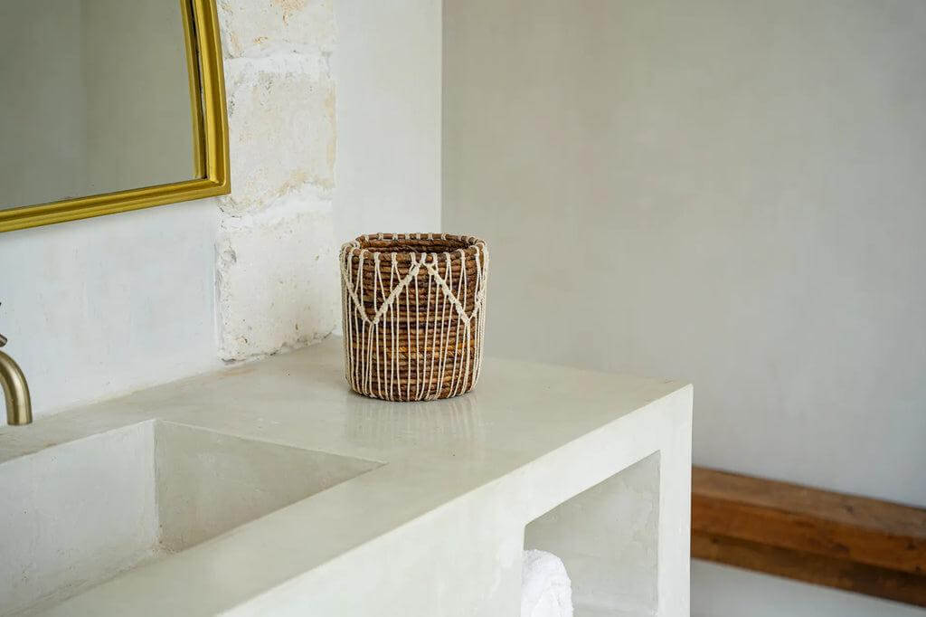 Alt Tag: Handgemaakte mand van bananenbladeren en katoen op witte wastafel, natuurlijke en elegante inrichtingselementen in badkamer.