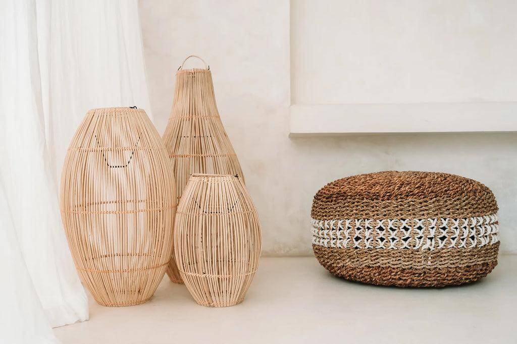 Gezellige macrame poef van zeegras met handgemaakt patroon naast decoratieve rieten manden. Ideaal voor binnengebruik.