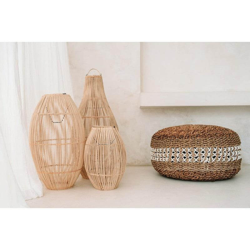 Natuurlijke macrame poef met zeegras en kruissteek patroon naast decoratieve manden.