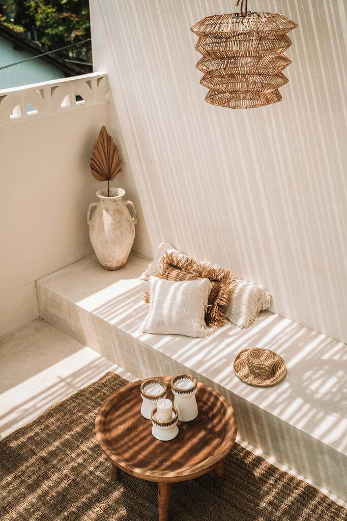Gezellige buitenruimte met rotan hanglamp, rustieke meubels en natuurlijke accenten in bohemienstijl. Perfect voor ontspannen momenten.
