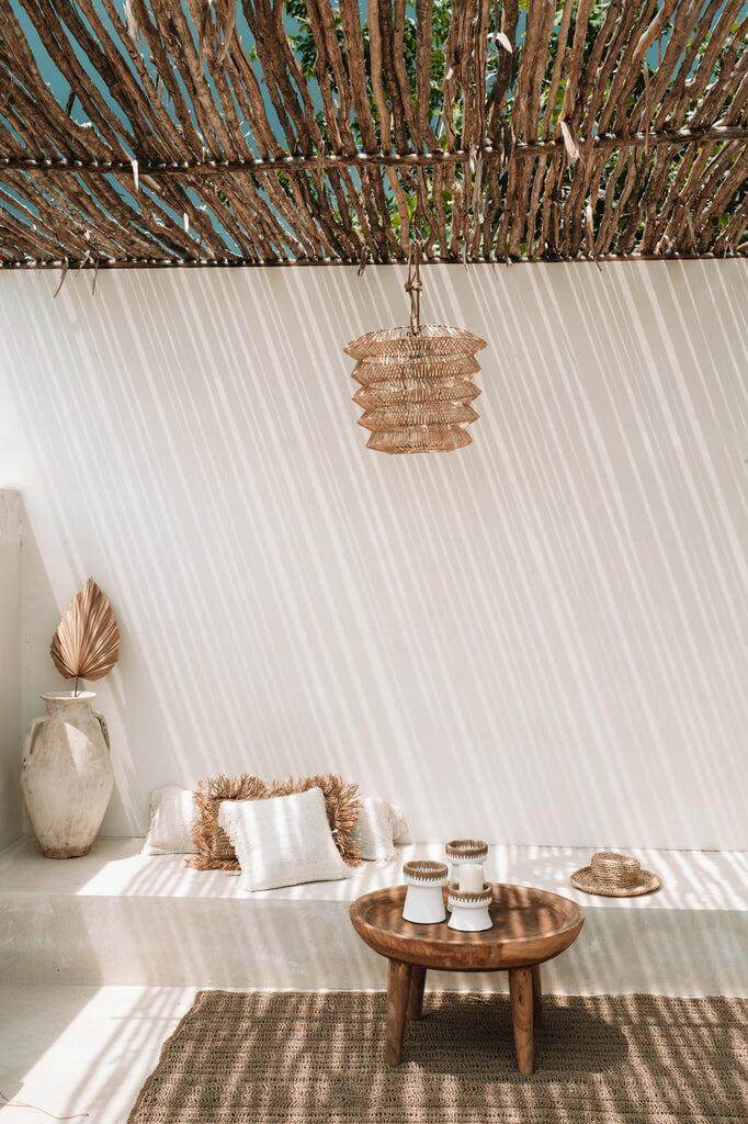 De Mad Moiselle rotan hanglamp boven een bohemien zithoek met natuurlijke elementen.