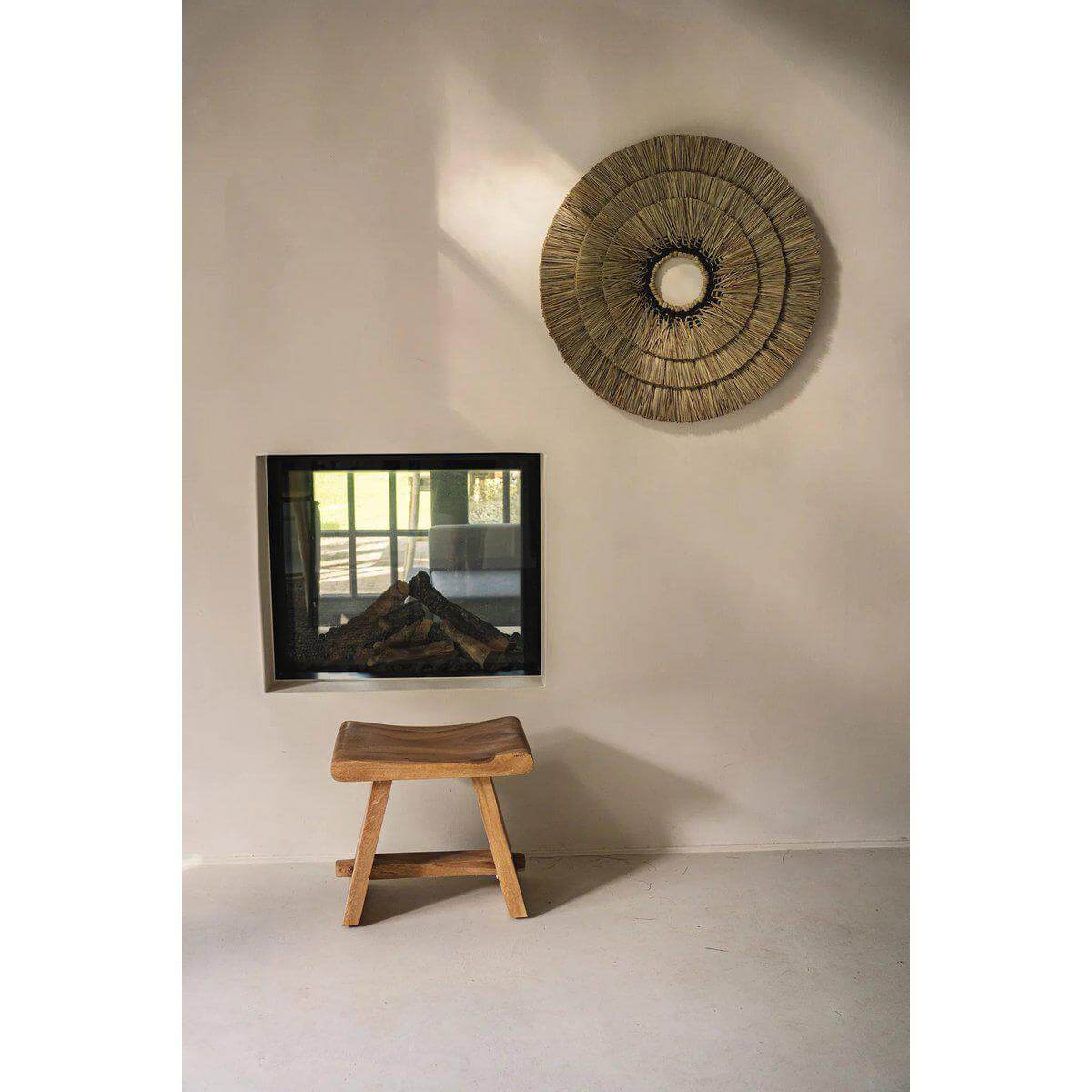 Handgemaakte Mengdong wanddecoratie in zwart katoen gecombineerd met gras, bohemian kuststijl aan muur met houten stoeltje.