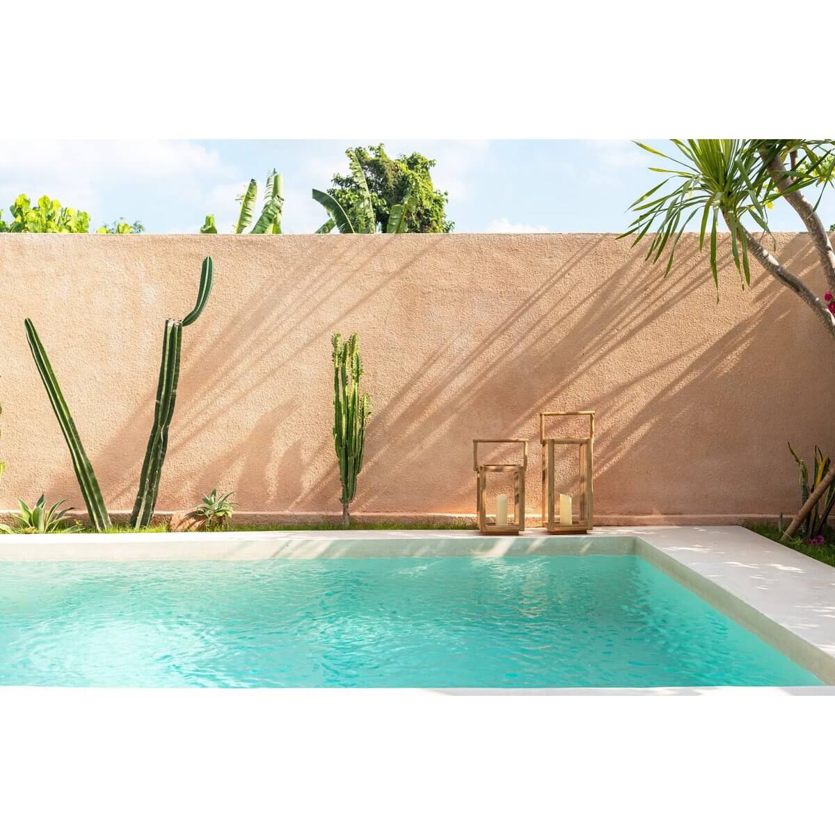 Tropical poolside scene with Bohemian Nusa Penida lanterns casting a warm glow, accented by cacti and lush greenery.