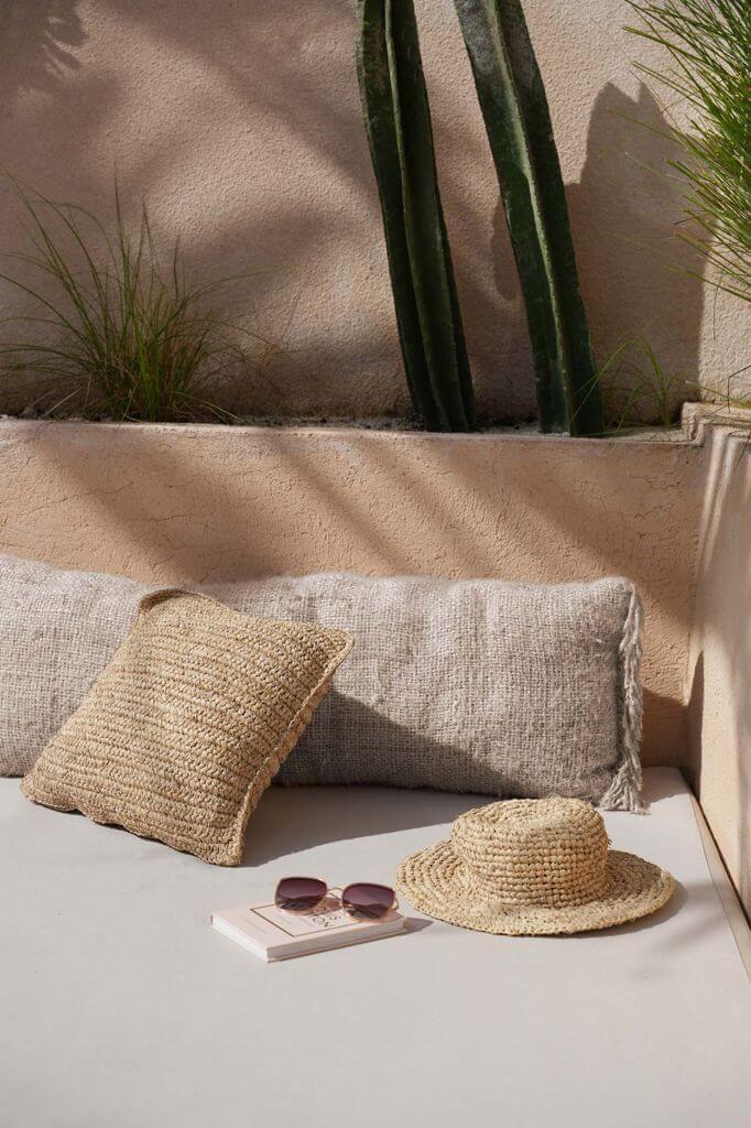 De Oh My Gee kussenhoes in beige op een patio, met boho-accenten en textuur, perfect voor stijlvolle interieurdecoratie, 35x100 cm.