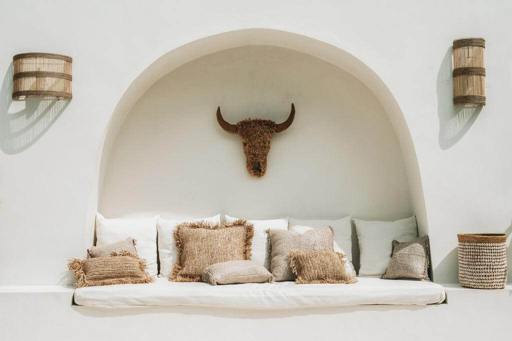 Boho zithoek met beige kussens, zachte katoenen hoezen, en een rustieke stierschedel decoratie, perfect voor een chique inrichting.