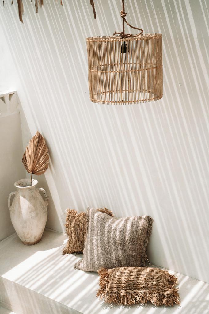 Boho chic ruimte met beige kussenhoes en rieten lampenkap, perfecte aanvulling voor stijlvolle interieurs.
