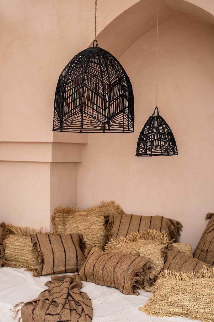 Gezellige boho-stijl zithoek met kussen met beige en zwarte patronen, omgeven door rieten hanglampen en natuurlijke texturen.