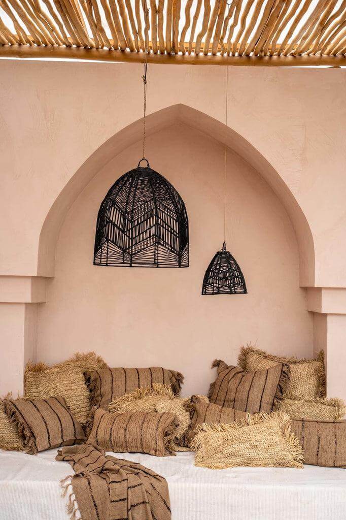 Gezellige bohemian kamer met rustieke kussens en sfeervolle hanglamp in beige en zwart, perfect voor chique interieurstijl.