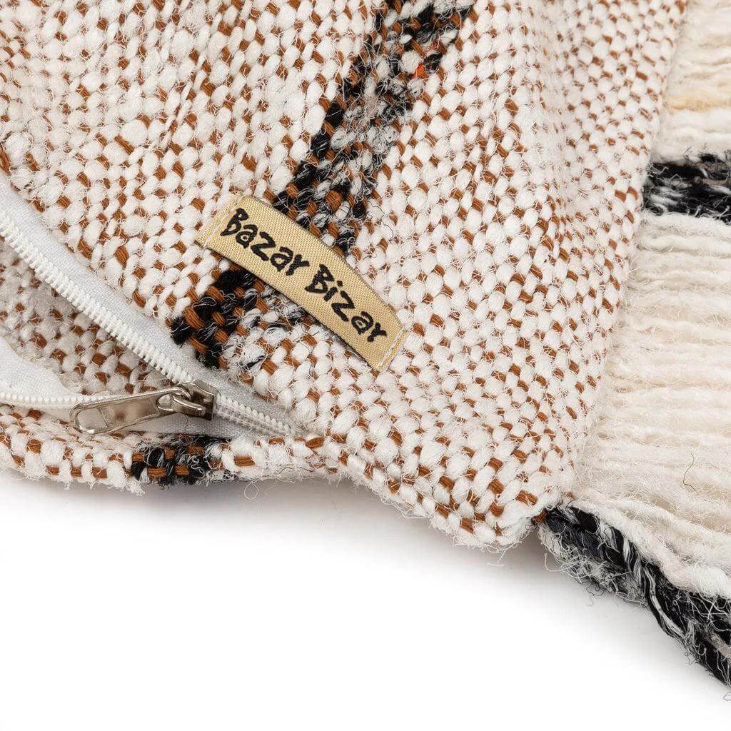 Close-up van bohemian katoenen kussenhoes in wit met rits en geweven patroon, ideaal voor een stijlvolle woondecoratie.